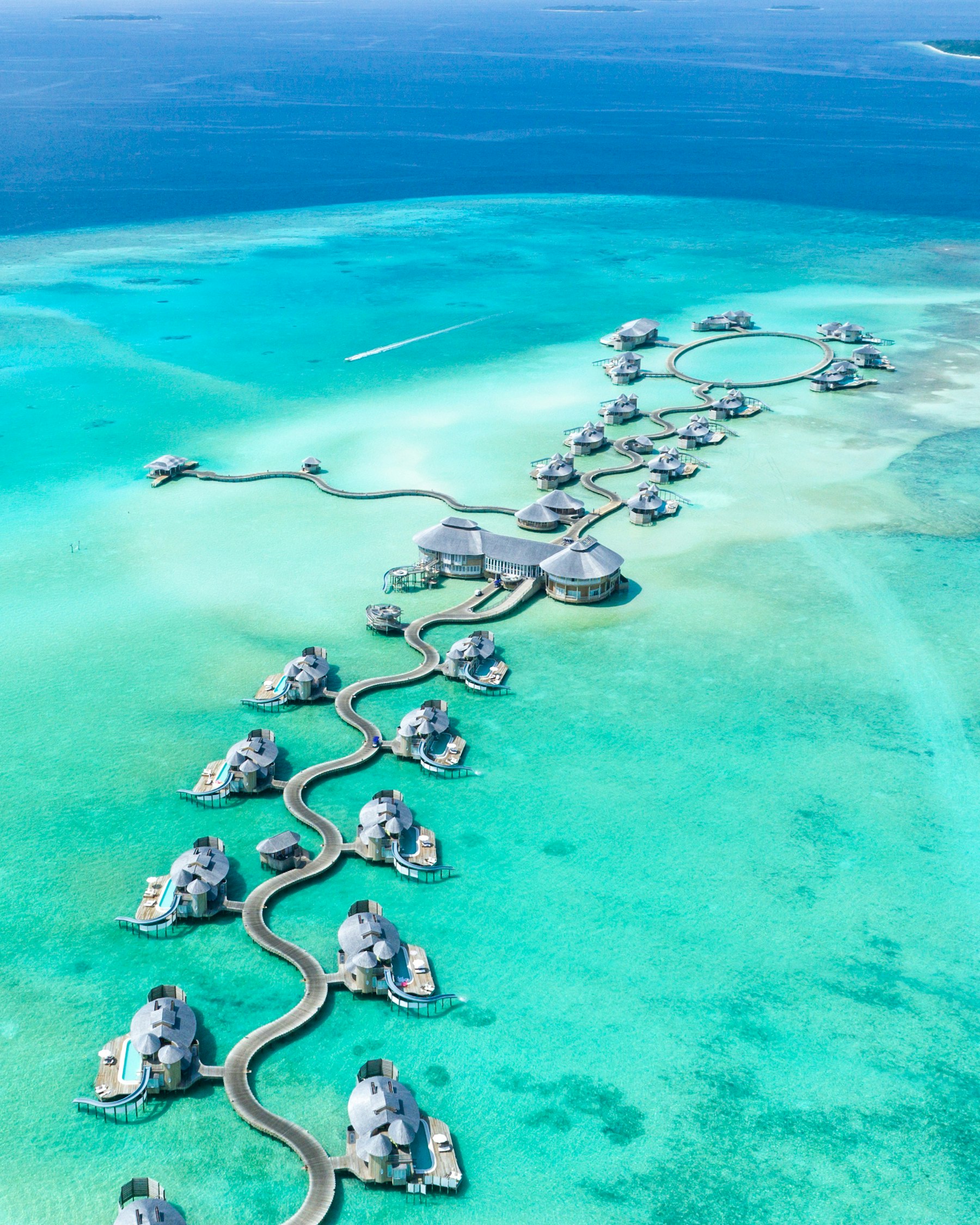 Overwater villas linked by walkways in a turquoise Maldives lagoon