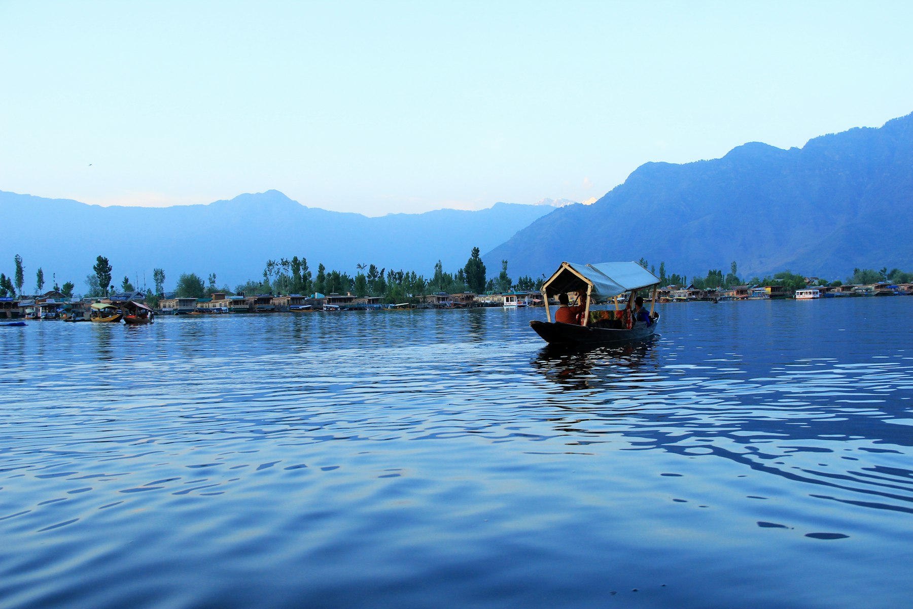 A shikara on Dal Lake with the Kashmir mountains beyond